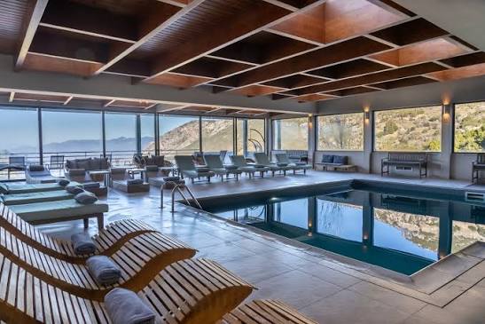 Indoor pool with sun loungers and floor-to-ceiling mountain views