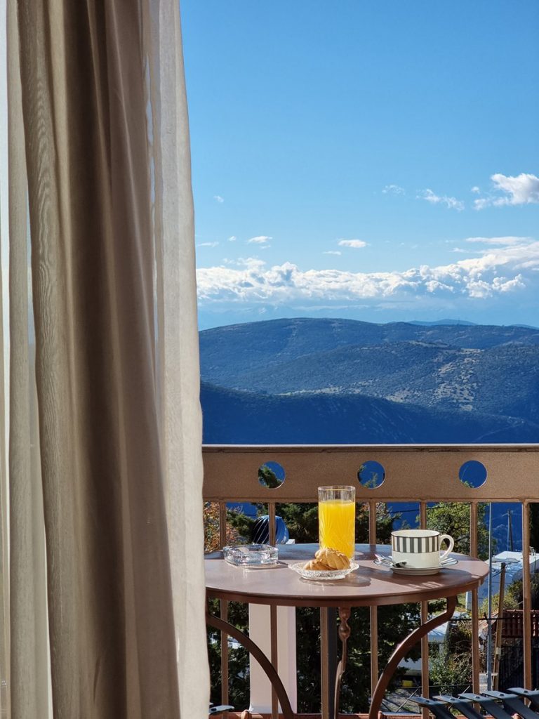 Breakfast on a balcony table with a view over blue mountains