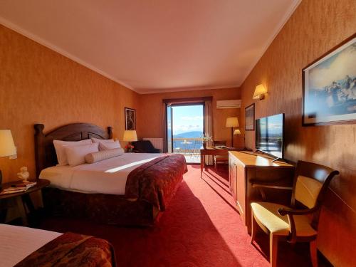 Guest room with a wooden bed, red carpet and a balcony with mountain views
