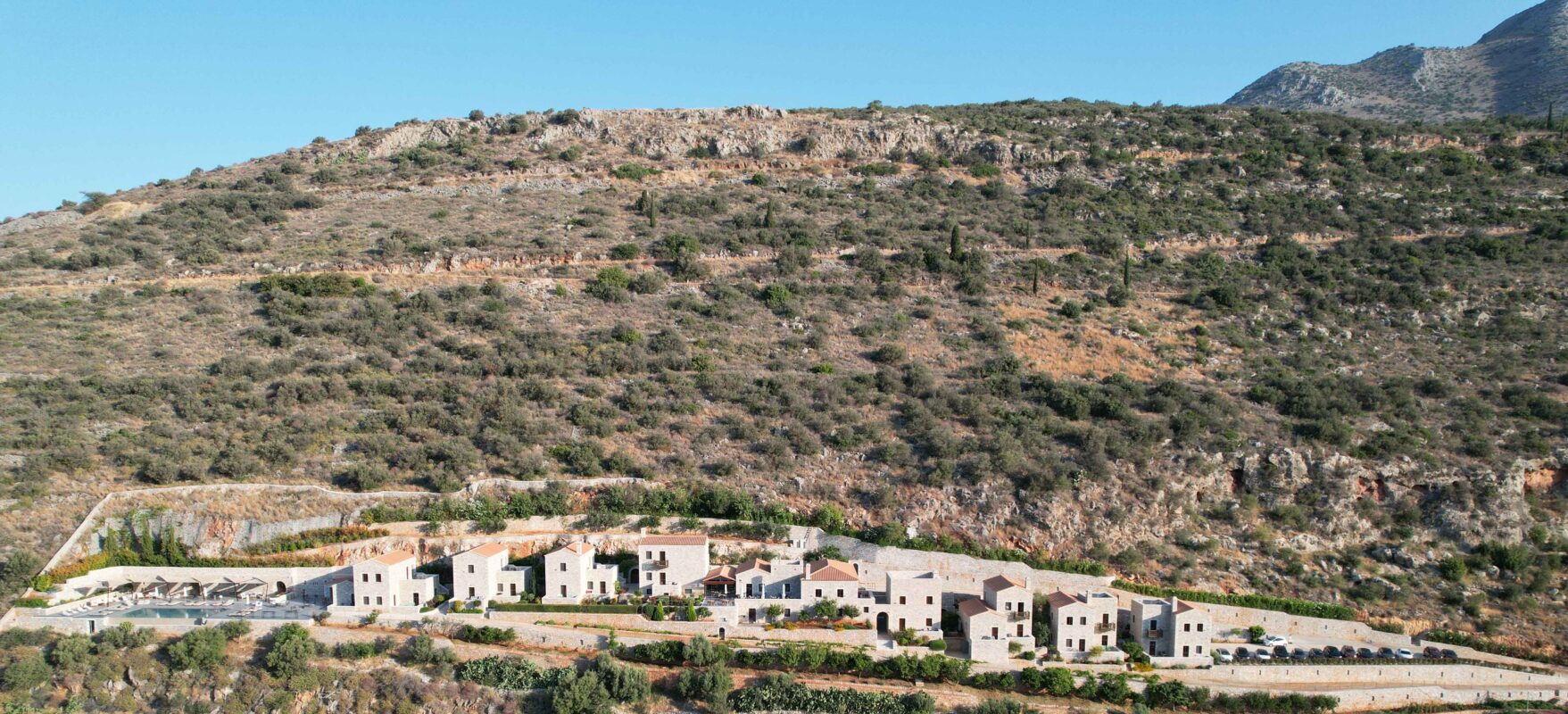The hotel's stone buildings set into a terraced hillside under a blue sky