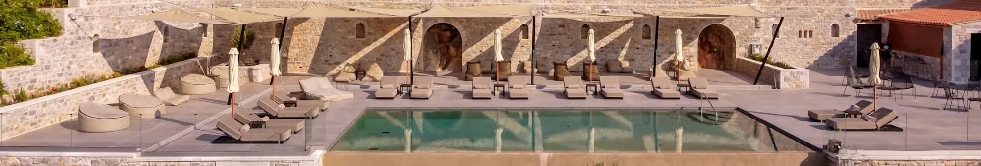 Pool terrace with sun loungers, white sails and stone arches