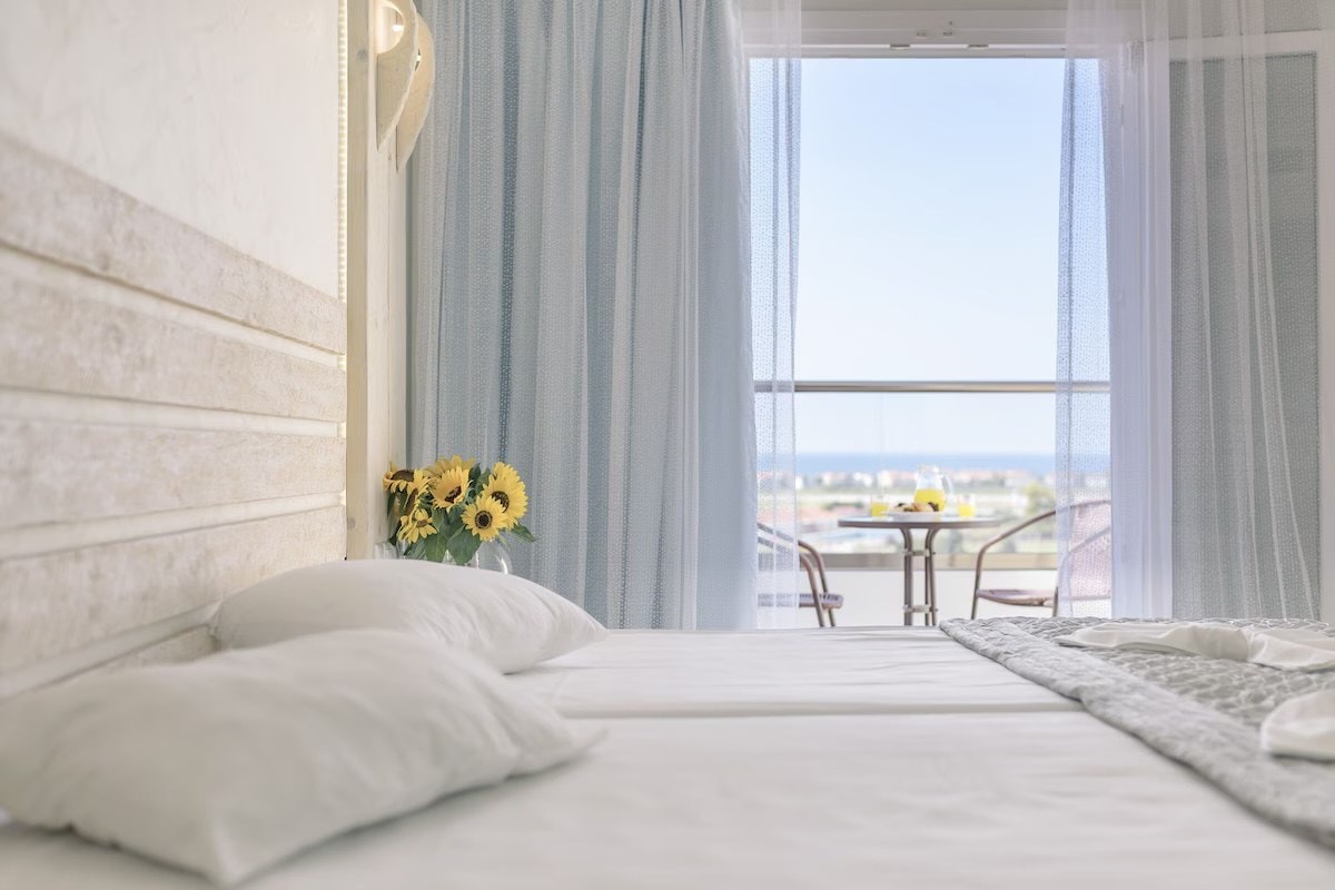 Bright bedroom with sunflowers and a balcony looking out to the sea